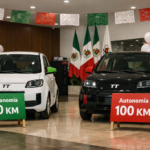 Dos coches eléctricos compactos en un showroom, uno con rótulo 50 km y otro 100 km, con colores de México